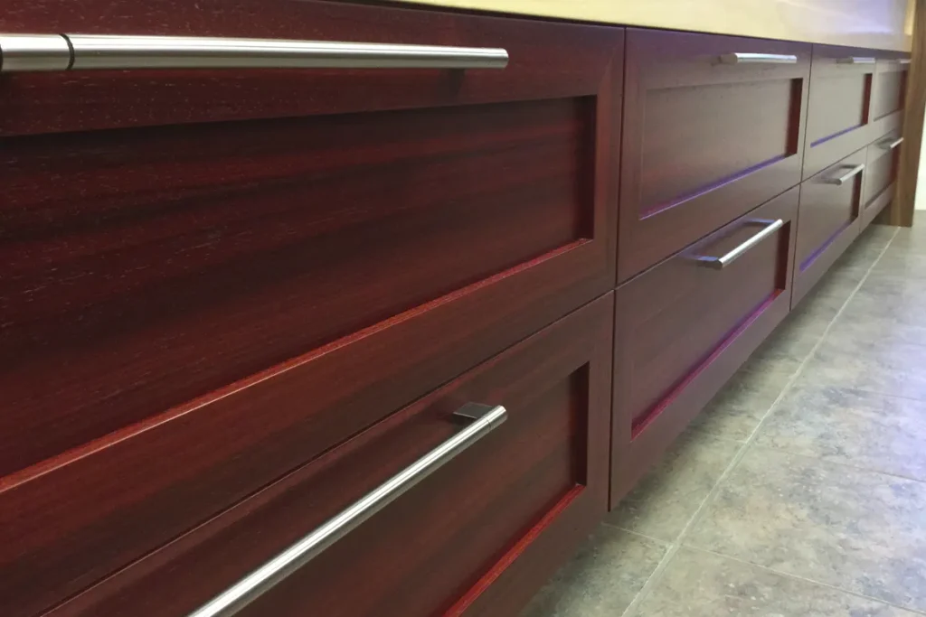 Aménagement de mobilier en placage de Padauk, avec finition satinée et couleur rouge profonde mettant en valeur le veinage